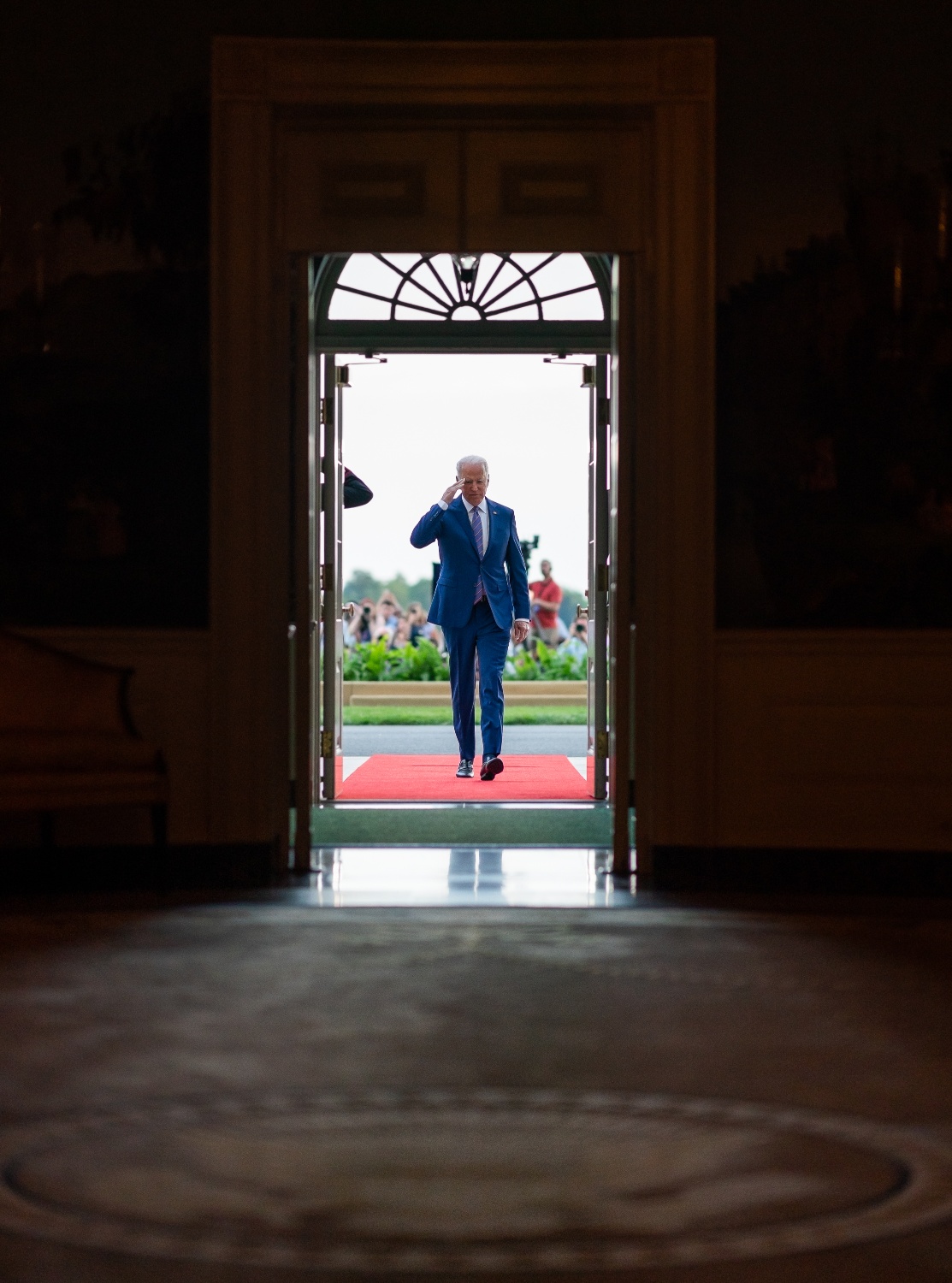 President Biden walking through door, saluting to military personnel